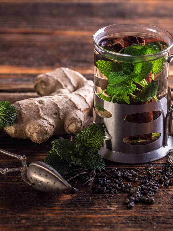 Cup of herbal tea with fresh mint on wooden table
